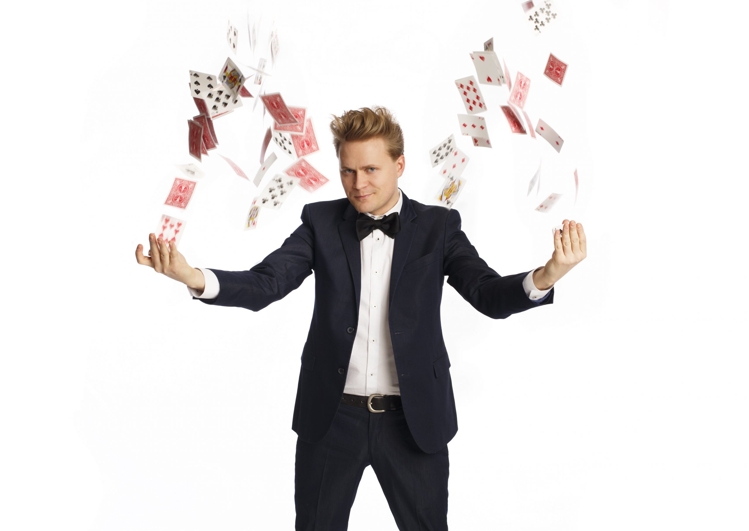 Man has both arms out stretched while a deck of cards float about his hands