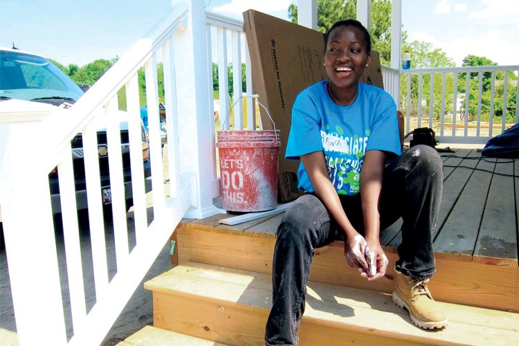 A student volunteer sits on the porch on a home she helped built.