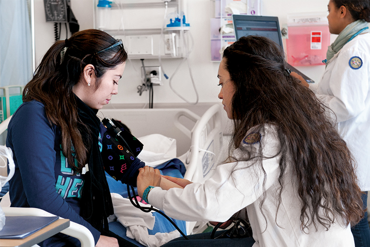 Nursing students pratice taking a patient's blood pressure.