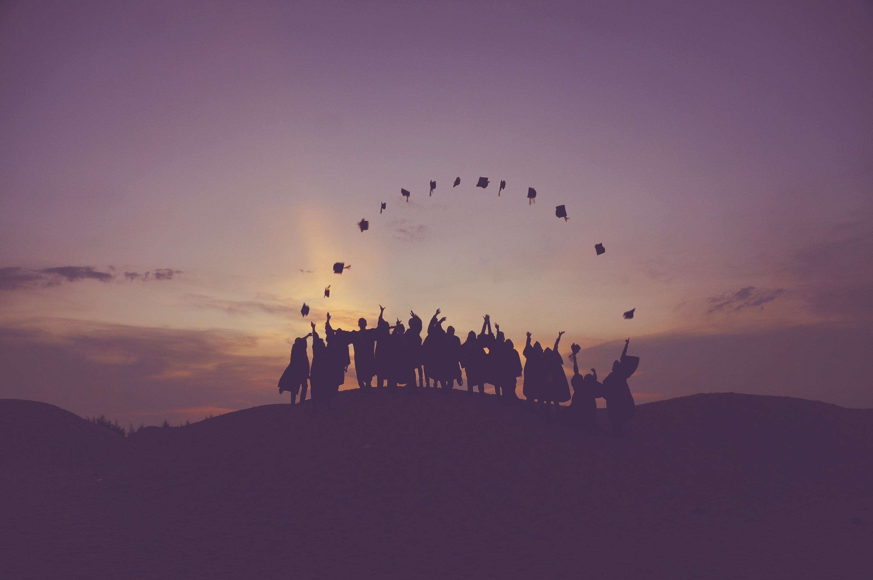 Silhouette of People Throwing Graduation Caps