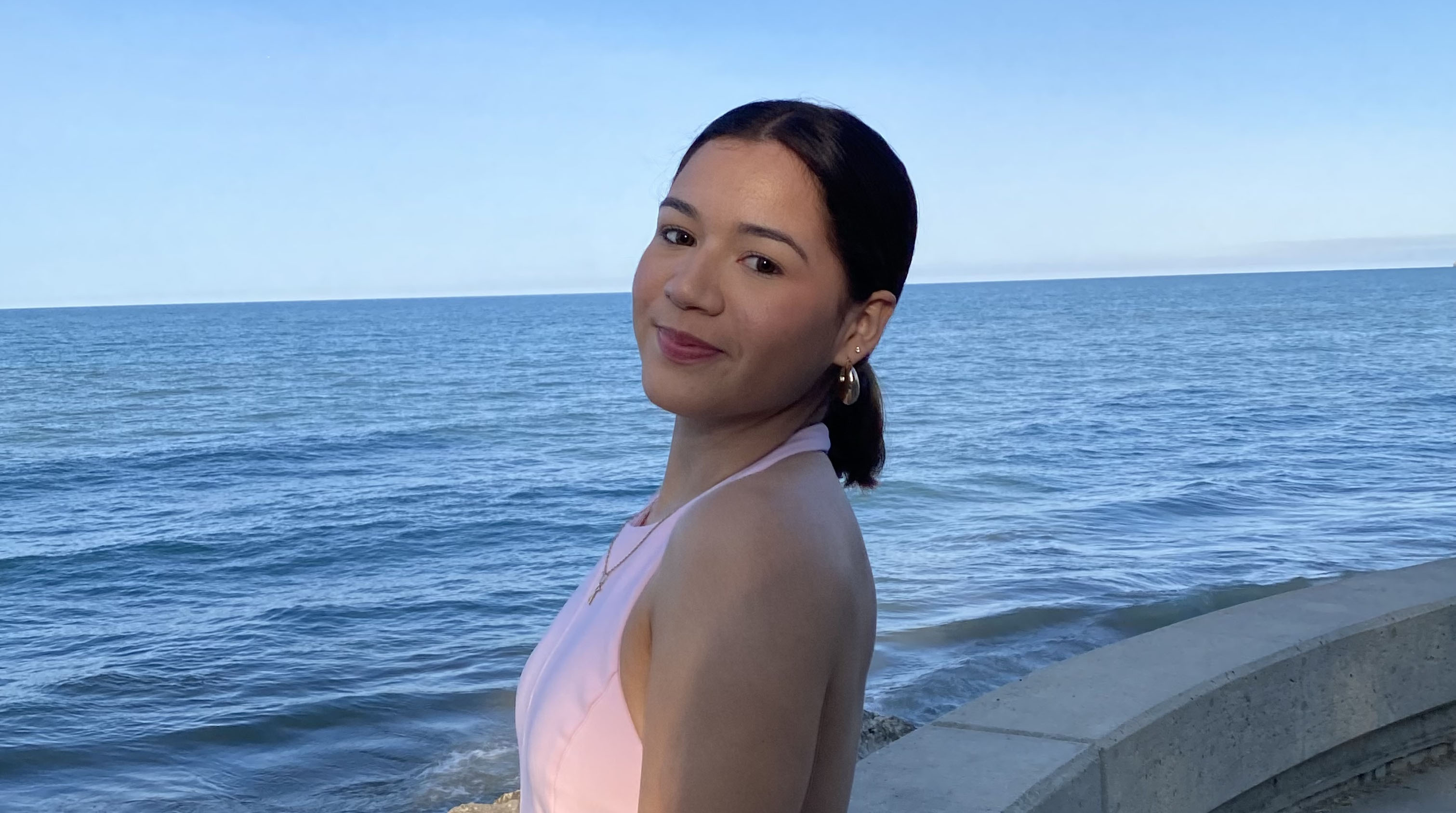 Kenia stands outside with the ocean behind her