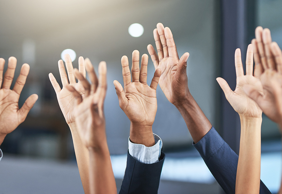 a closeup of several diverse hands raised