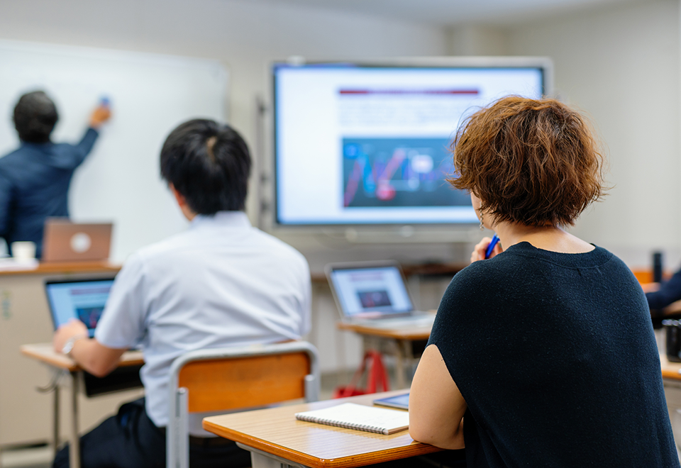 Students in a classroom watching an instructor at a whiteboard